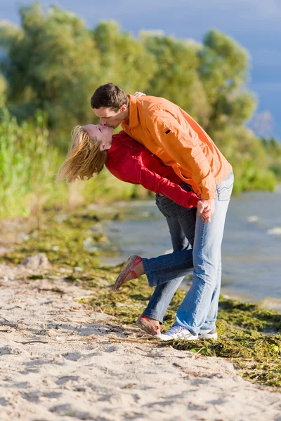 年轻爱的情侣在海岸的河上亲吻 — 图库照片