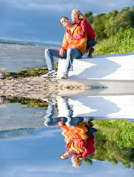 Junges Liebespaar sitzt auf Boot am Ufer des Flusses — Stockfoto