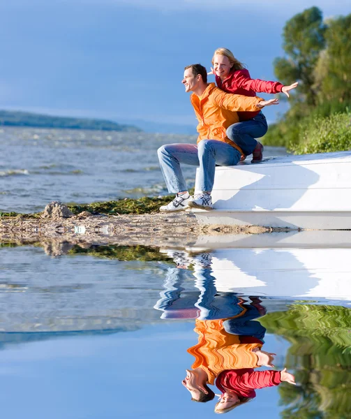 Joven amor pareja sentarse en barco en costa de río —  Fotos de Stock