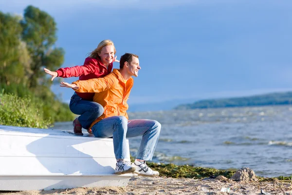 年轻爱的情侣坐在海岸的河的船上 — 图库照片