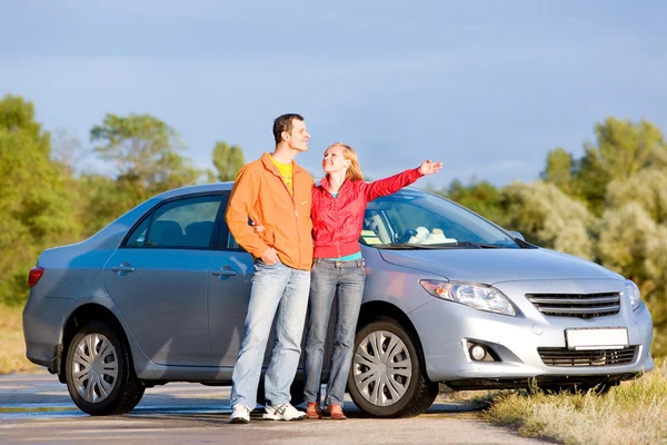 彼らの新しい車との幸せな若いカップル 女性は手で何かを示しています 上記のものを見てください — ストック写真