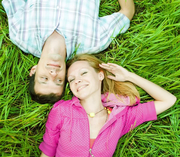 年轻的爱情侣躺在户外的绿草上. — 图库照片