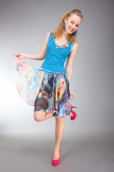 Gyönyörű fiatal nő könnyű ruhát, szürke háttérrel — Stock Fotó