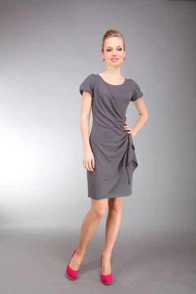Mooie jonge vrouw in lichte jurk met grijze achtergrond — Stockfoto