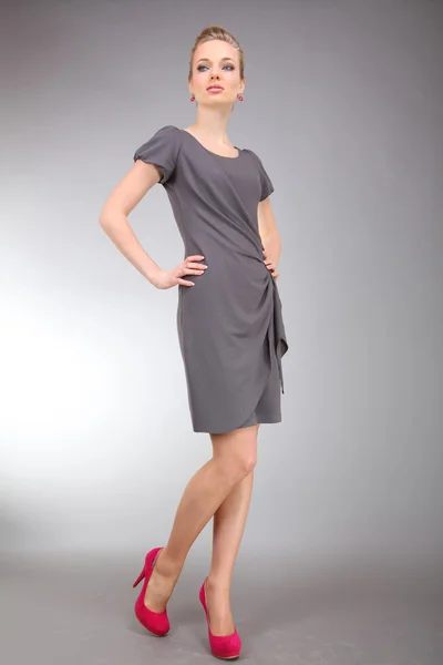 灰色の背景と光のドレスで美しい若い女性 — ストック写真