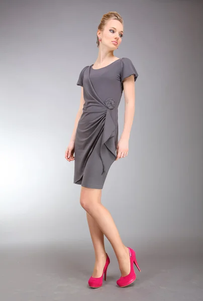 Vacker ung kvinna i ljus klänning med grå bakgrund — Stockfoto