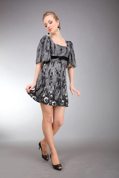 灰色の背景と光のドレスで美しい若い女性 — ストック写真