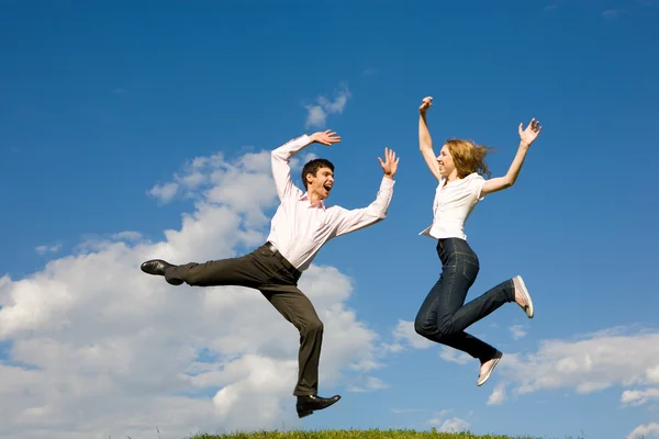 Felice coppia sorridente saltando nel cielo blu Fotografia Stock