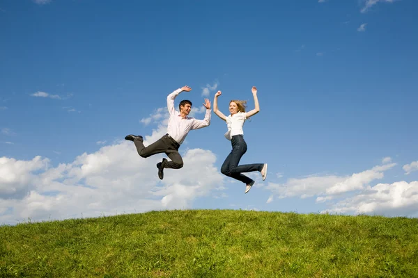 Felice coppia sorridente saltando nel cielo blu Immagini Stock Royalty Free