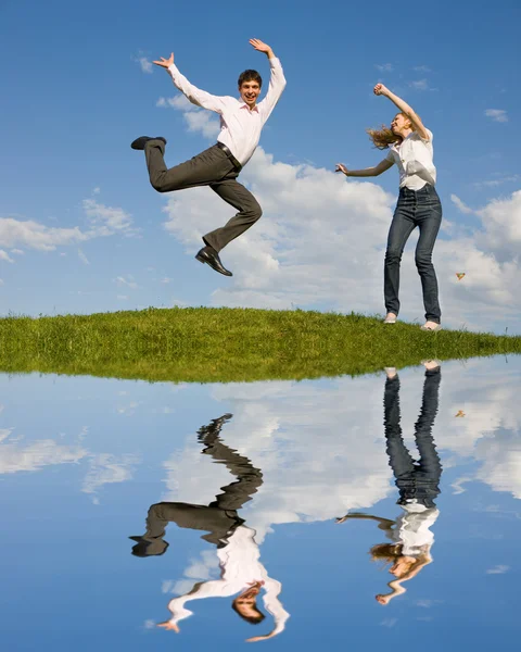 Joyeux couple souriant sautant dans le ciel bleu Image En Vente