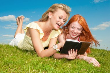 Notebook açık havada iki güzel kızla. Yeşil gr üzerinde yatıyordu