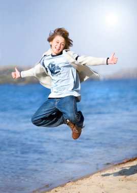 Happy jumping boy on beach clipart