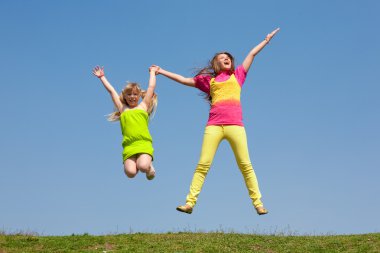 iki kız yeşil çayır üzerinde atlama