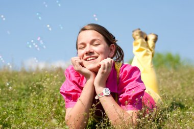 çok gülümseyen kızın rahatlatıcı yeşil çayır çiçeklerle dolu. yumuşak odak. gözlere odaklanın.