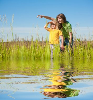 Happy mother and daughter on field. Reflected in Water. clipart