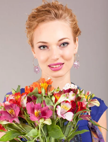 Gyönyörű fiatal nő, a fény a szürke háttérben virágok ruha — Stock Fotó