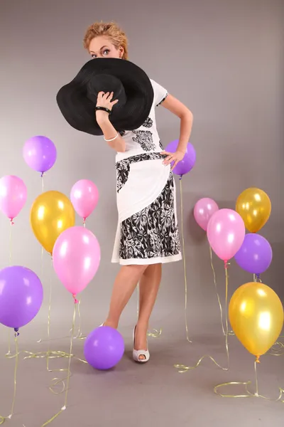 Beautiful young girl in light dress a hat on background balloons — Stock Photo, Image