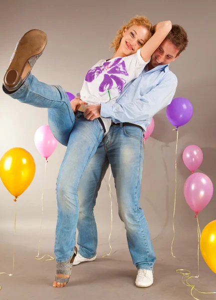 Молода любов пара посміхається з повітряними кулями — стокове фото