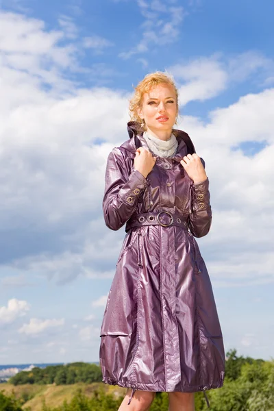 コートの美しい若い女性 青い空を背景に — ストック写真
