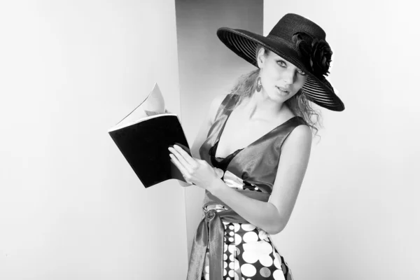 Mladá žena v šatech a černý klobouk. v ateliéruung kvinna i klänning och svart hatt. i studion — Stock fotografie