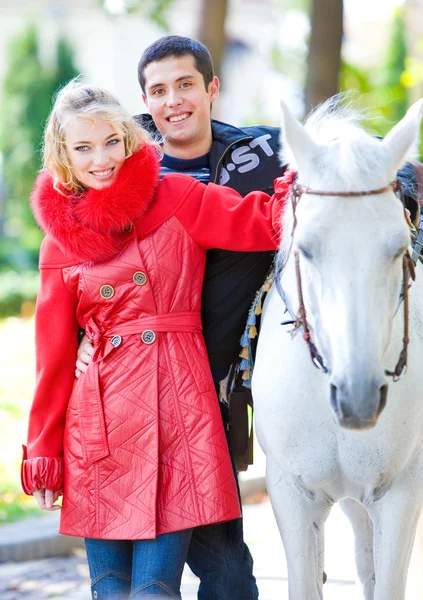 Jeune amour Couple souriant près d'un cheval — Photo