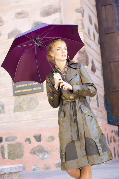 Schöne junge Frau mit Regenschirm vor dem Hintergrund der bui — Stockfoto
