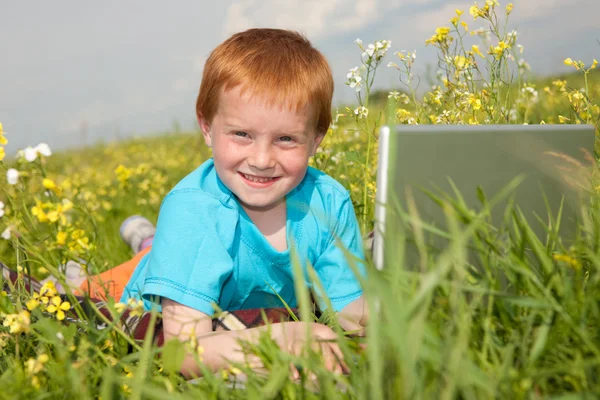 草原にラップトップ コンピューターを持つ子供の笑顔 — ストック写真