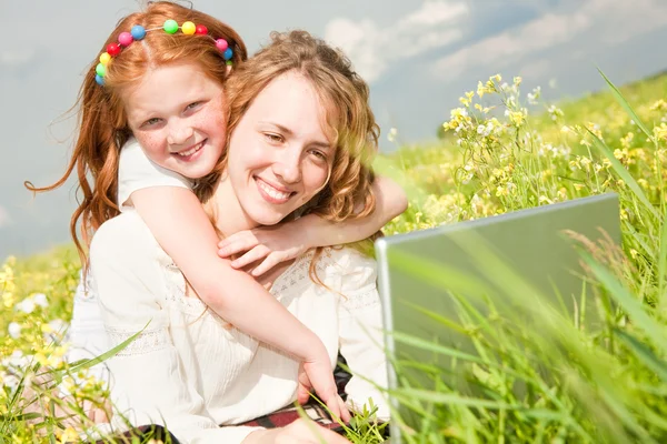 Matka a dcera ležela na trávě s notebook — Stock fotografie