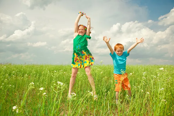 Två guldhåriga barn leker ute på fältet — Stockfoto