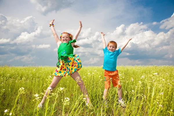 Två guldhåriga barn leker ute på fältet — Stockfoto