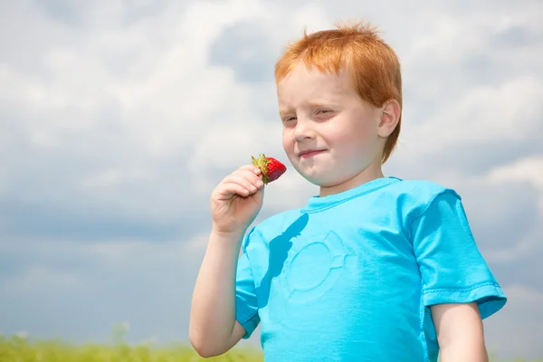 Pojke som äter en jordgubbe. mjukt fokus. fokusera på ögat. — Stockfoto