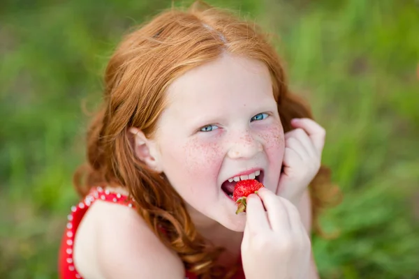 Meisje die een aardbei eet. Soft Focus Sea.... focus op oog. — Stockfoto