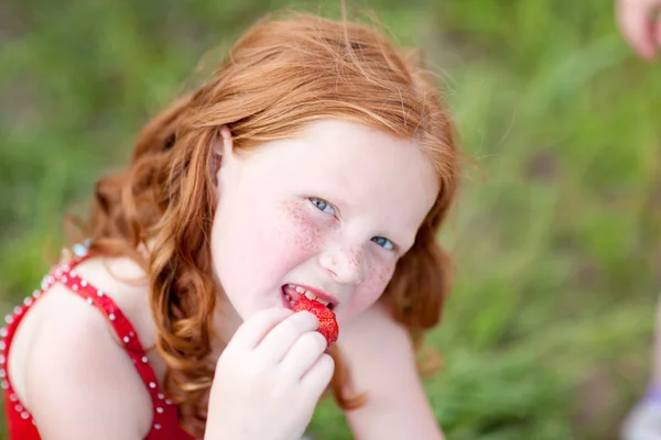 Girl which eats a strawberry. Soft focus. Focus on eye. — Stock Photo, Image