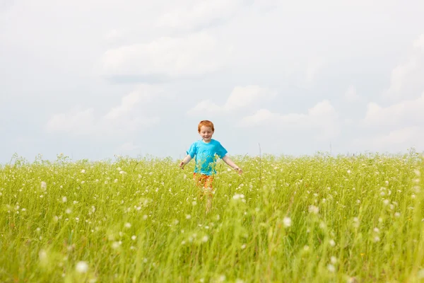 Lycklig pojke kör i fältet — Stockfoto