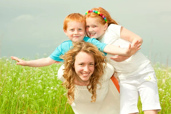 Moeder met kinderen gaat op veld — Stockfoto