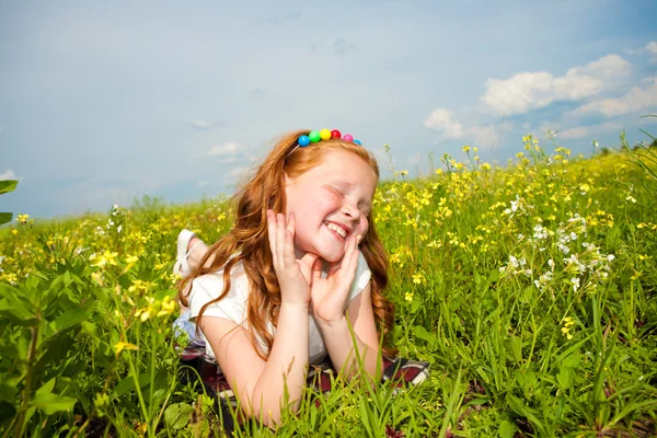Lilla vackra flicka utomhus. låg på det gröna gräset. — Stockfoto