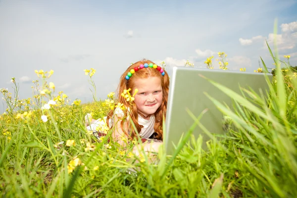 草原に休んでノート パソコンを持つ少女 — ストック写真