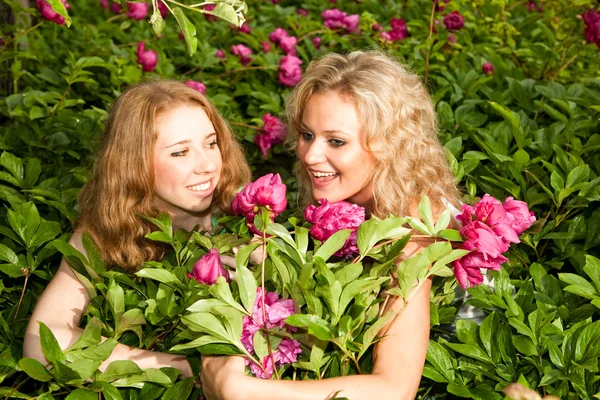 两个快乐年轻妇女在鲜花 — 图库照片