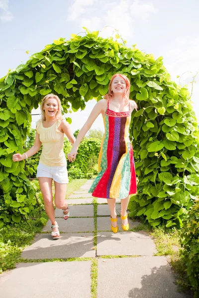 Duas jovens felizes estão correndo em um parque — Fotografia de Stock