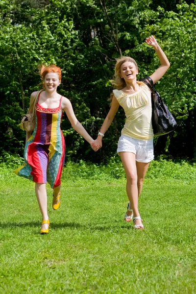 Twee gelukkige jonge vrouwen zijn runing in een park — Stockfoto
