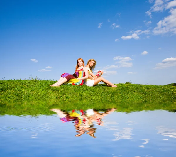 Duas meninas bonitas com notebook ao ar livre. Sentado no verde — Fotografia de Stock
