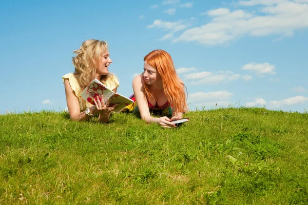 Dwie piękne dziewczyny z notebooków na zewnątrz. leżał na gr zielony — Zdjęcie stockowe