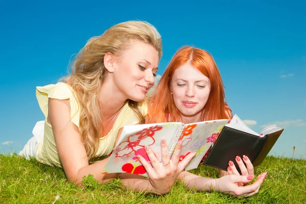 Δύο Όμορφα Κορίτσια Σημειωματάρια Εξωτερικούς Χώρους Βάλτε Στο Πράσινο Γρασίδι — Φωτογραφία Αρχείου