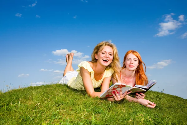 两个漂亮的女孩与户外的笔记本。躺在绿色的 gr — 图库照片