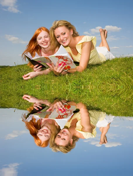 Dvě krásné dívky s notebooky venku. ležela na zelené gr — Stock fotografie