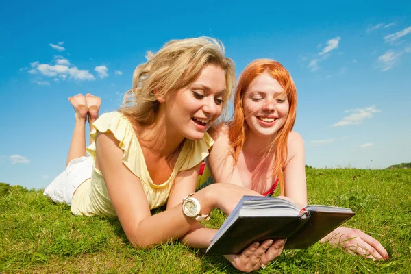 Twee mooie meisjes met laptops buitenshuis. Leg op de groene gr — Stockfoto