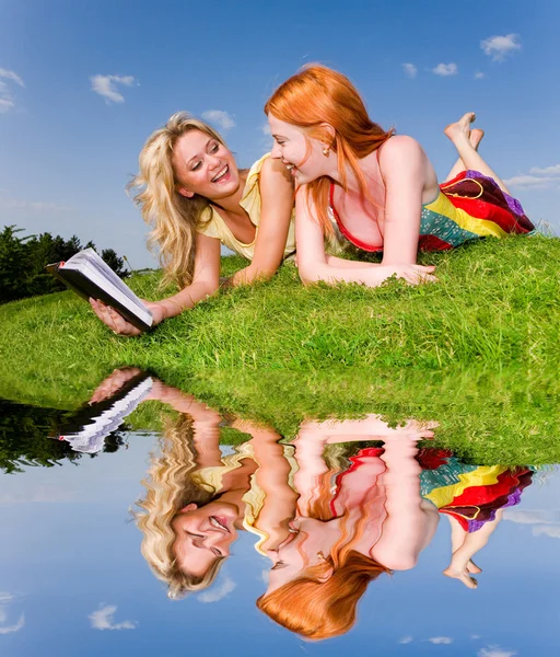 Deux belles filles avec ordinateur portable à l'extérieur. Allongez-vous sur la gra verte — Photo