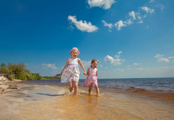 Милі дівчата грають у хвилях на морі — стокове фото