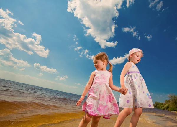 Two cute sisters play in waves on sea — Stock Photo, Image
