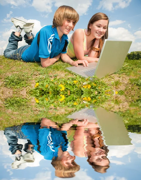 两个微笑少年与笔记本电脑在草地上休息. — 图库照片